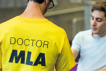 MLA staff doctor in a yellow t-shirt attending to a student