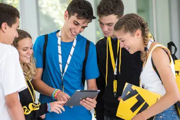 Group of teenage students with MLA lanyards looking at a tablet together