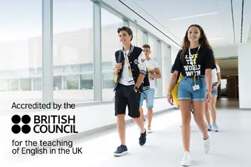 Students walking through a bright corridor with the British Council accreditation logo
