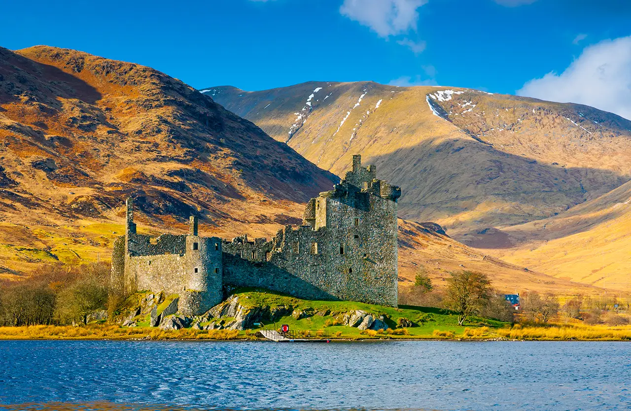 Kilchurn Castle ruins beside a loch with mountains in the Scottish Highlands