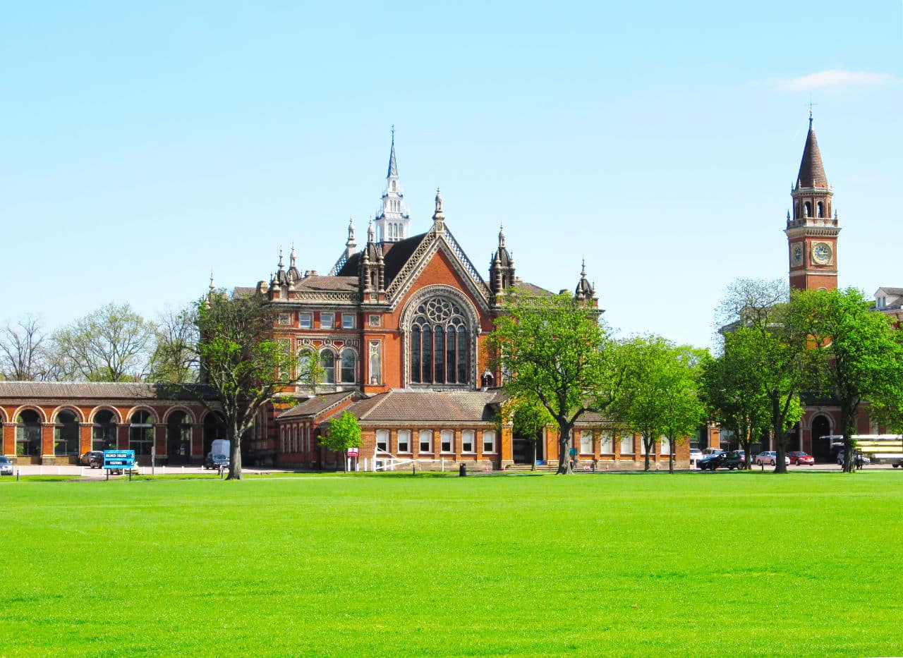 Dulwich College red-brick Victorian buildings and clock tower beyond a wide green lawn