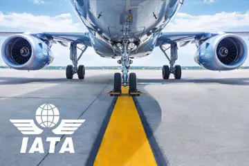 IATA logo over a front view of an airliner parked on the tarmac