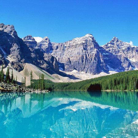 Turquoise Moraine Lake reflecting snow-capped Rocky Mountains and pine forest in Canada